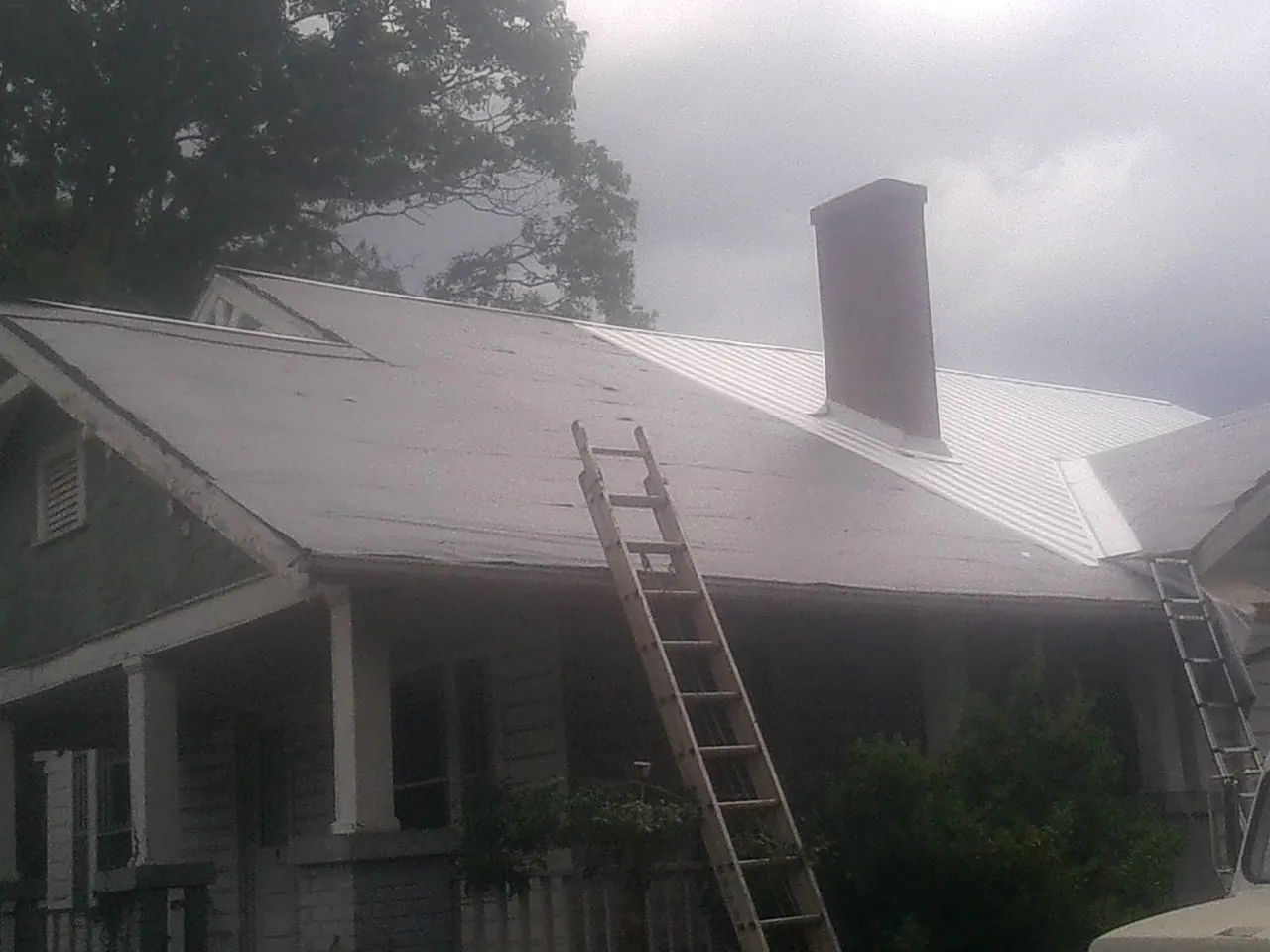 Ladders against a metal roof on an older home with a brick chimney in Varna