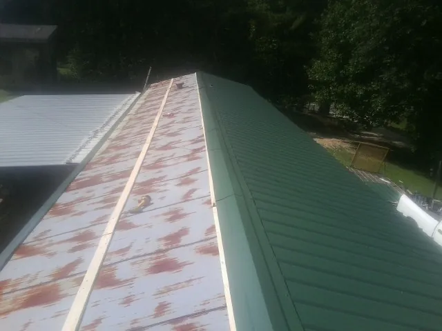 Old rusted panels beside newly installed green metal roofing — Wind Damage Roof Repair by Roofing Brothers in Varna