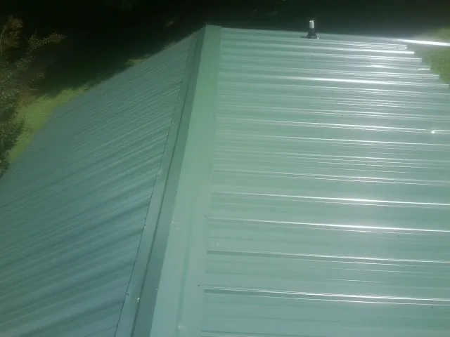 New green metal panels meeting at the ridge of a roof — Flat Roof Repair work by our crew in Varna