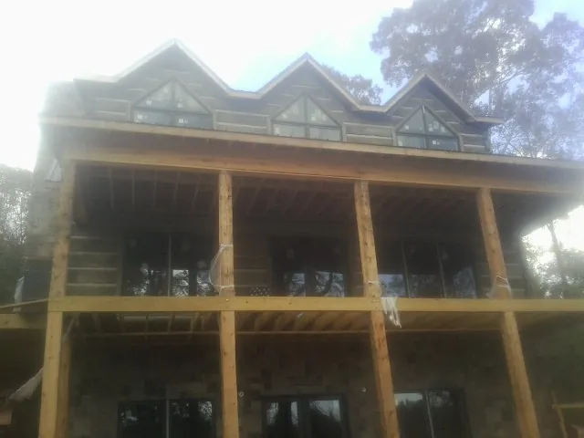 Dormers and porch framing on a large log home under construction — Roof Coating work by our crew in Varna