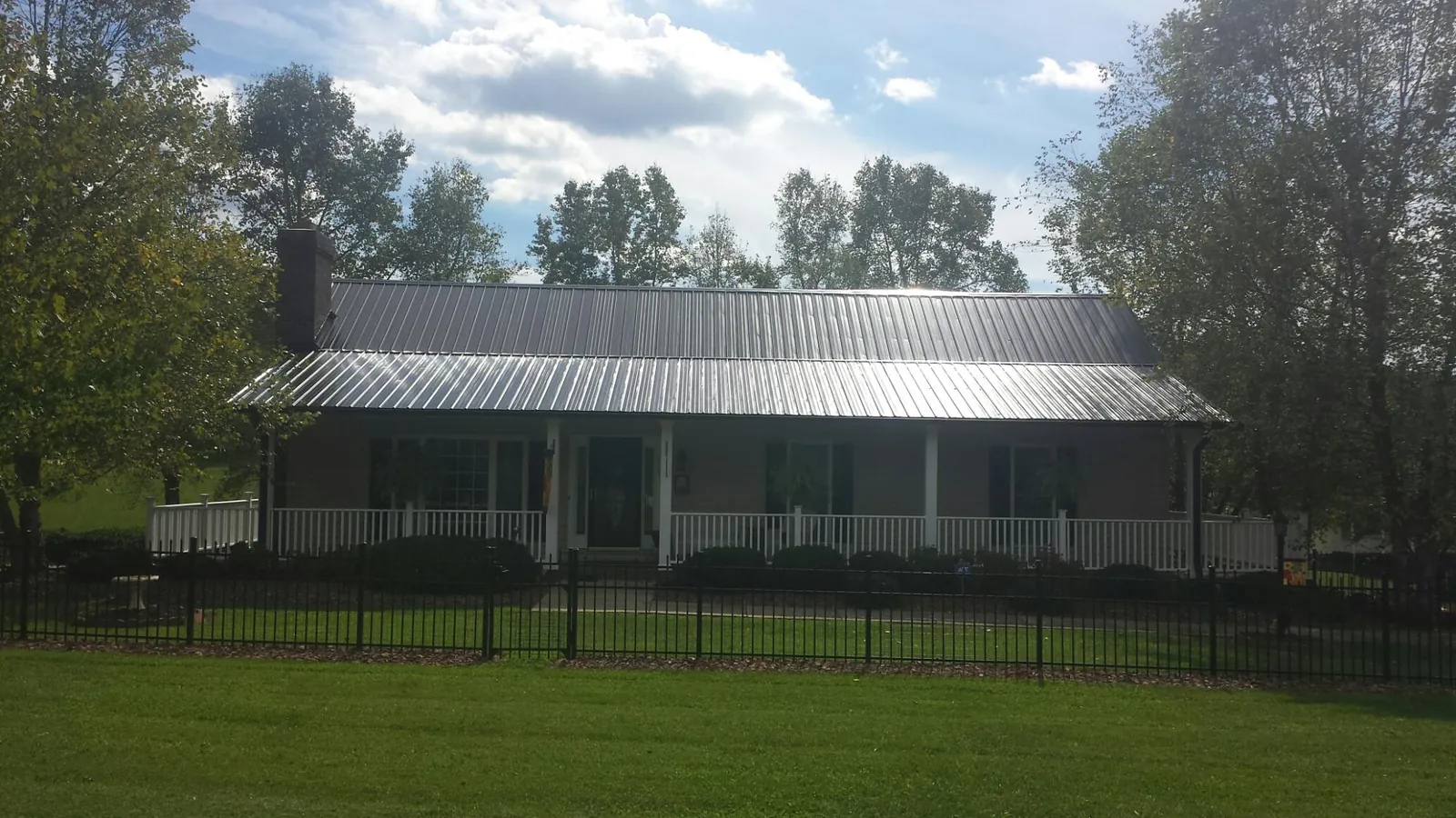 Gray metal roof on a brick ranch with a full width front porch — Gutter Guard Installation work by our crew in Varna