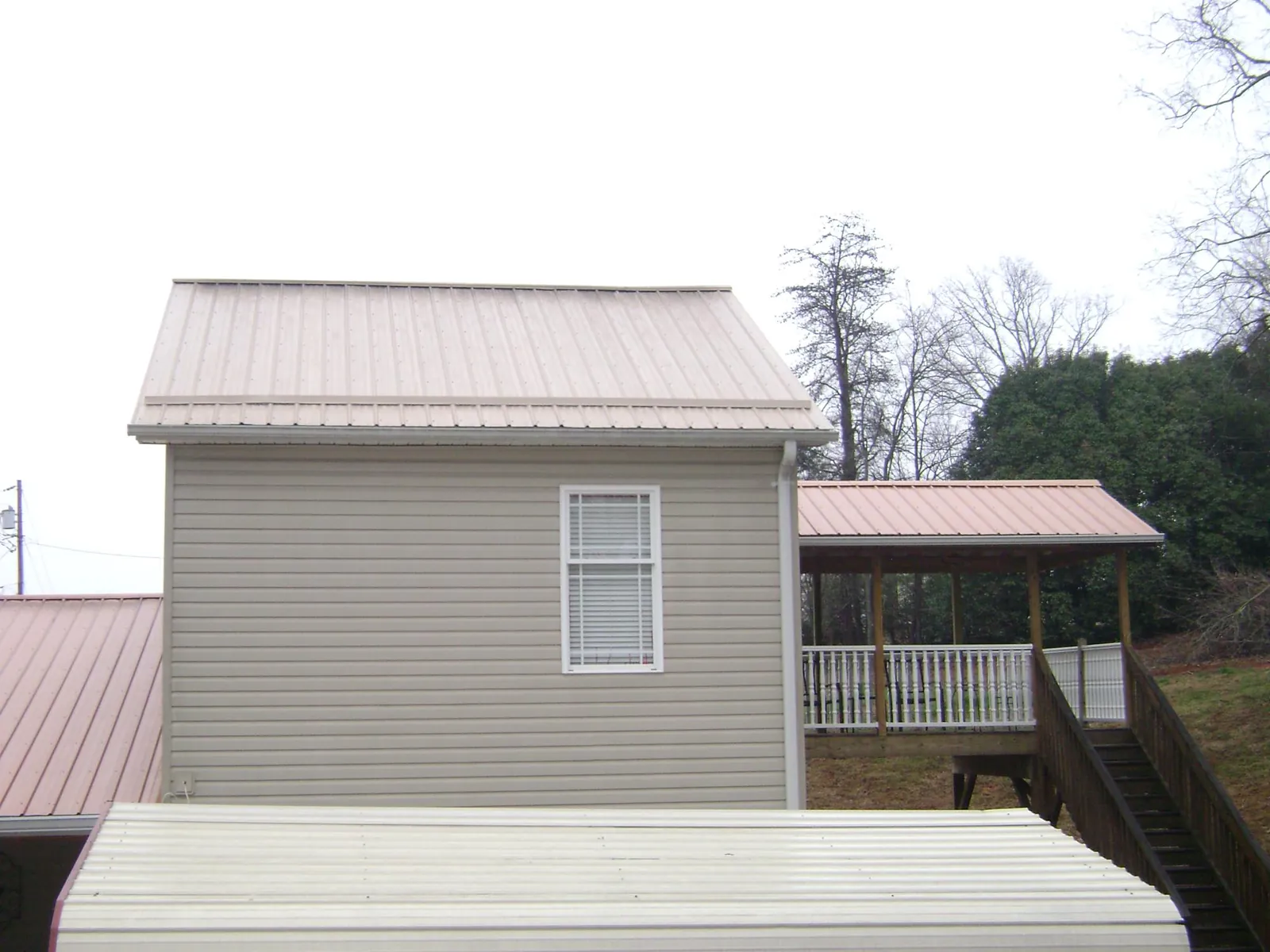 Tan metal roofs on a two story addition and attached porch, from a Roof Replacement job in Varna