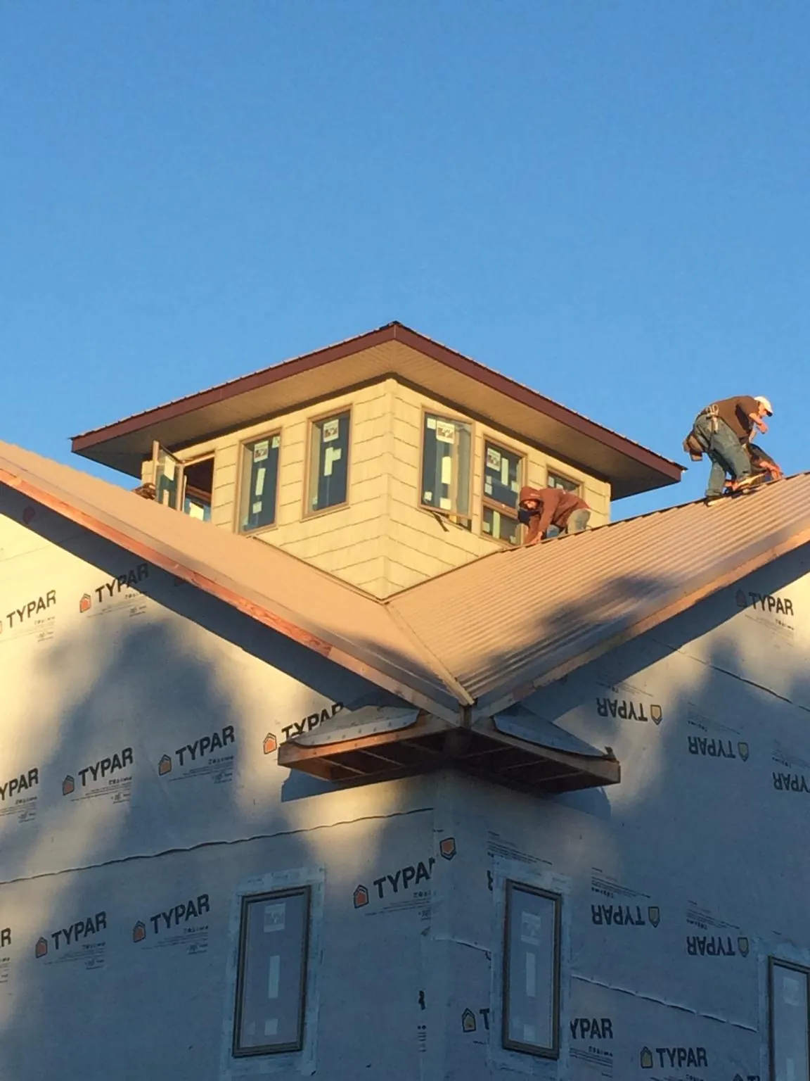 Roofers working around a rooftop cupola on a new metal roof at sunset — Roof Waterproofing in Varna by Roofing Brothers